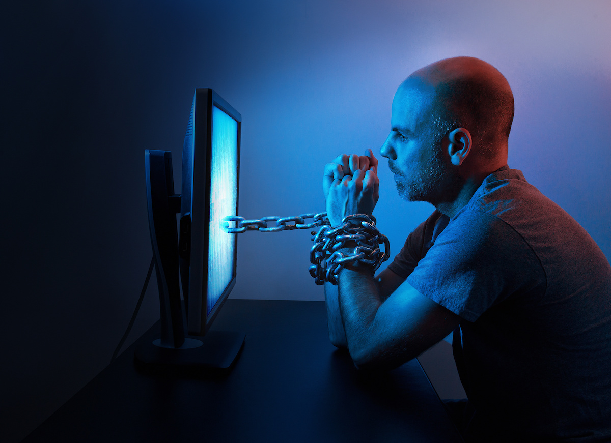 A man is chained to computer late at night.